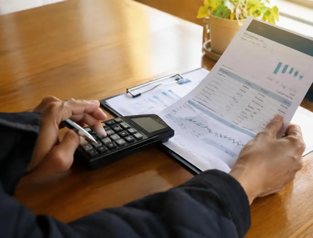 Persona revisando un recibo de luz con calculadora (imagen ilustrativa)